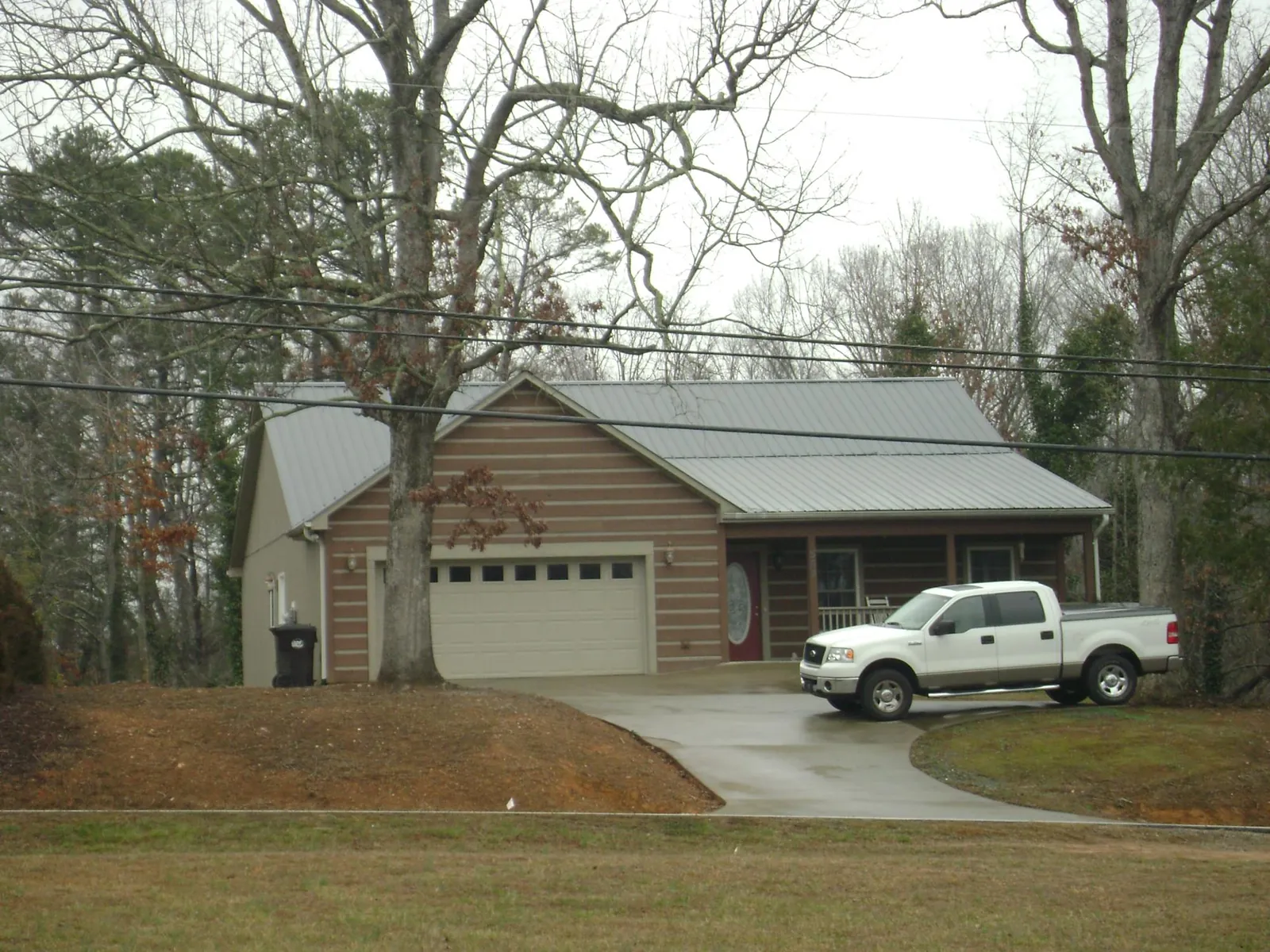 Gray metal roof on a log sided house with an attached two car garage in Hamden