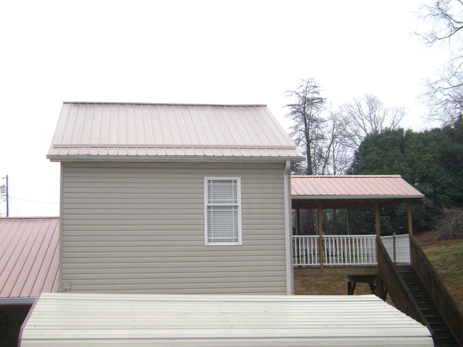 Tan metal roofs on a two story addition and attached porch, from a Roof Replacement job in Hamden