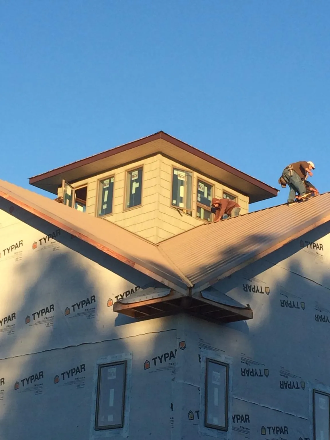 Roofers working around a rooftop cupola on a new metal roof at sunset — Roof Waterproofing in Hamden by Roofing Brothers